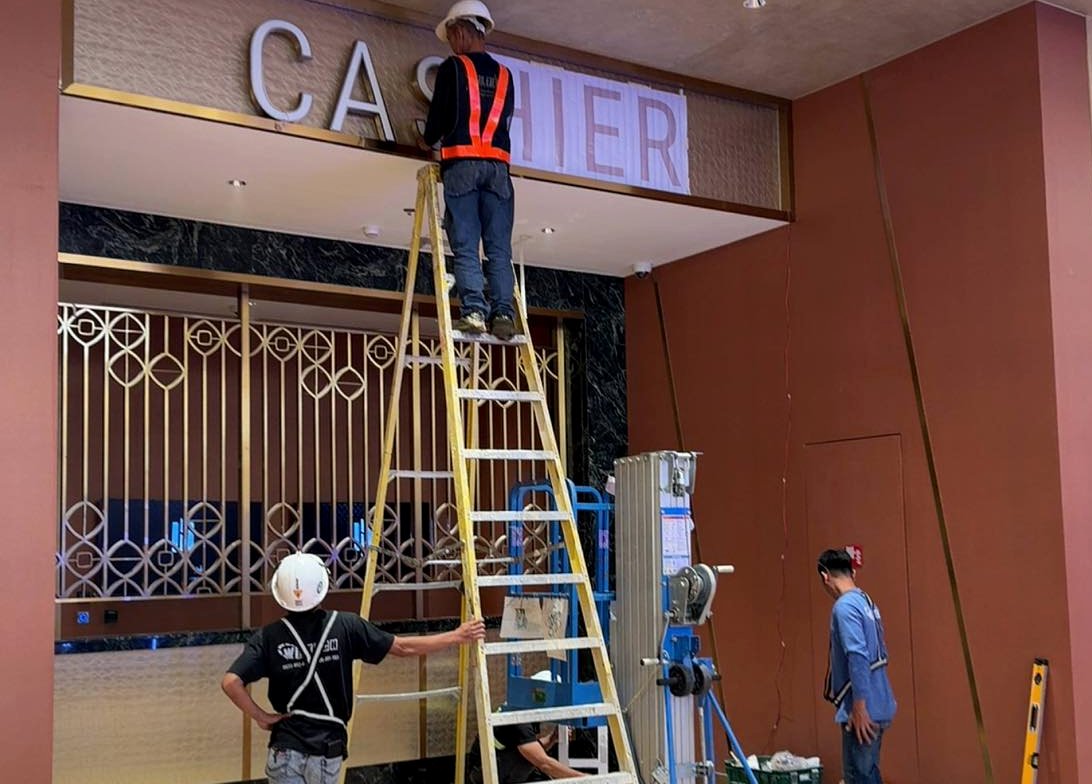 Wiltech crew installing the Cashier letters from ladder and lift