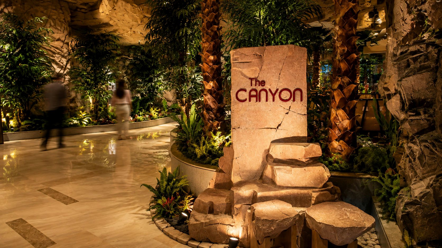 The Canyon finished entry monolith among palms and rockwork